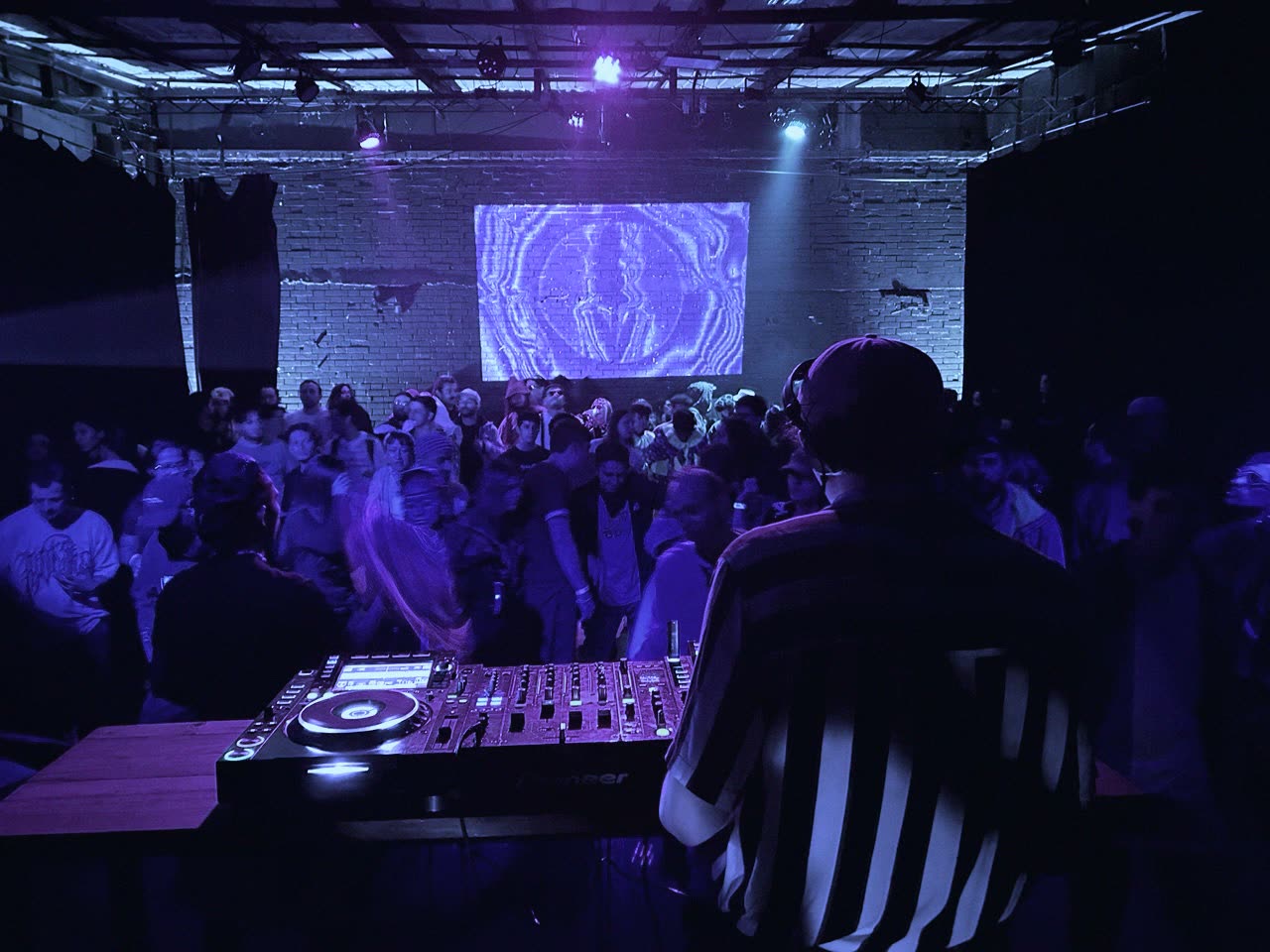 Beyond Me, liquid DnB DJ, at the decks in front of a packed room